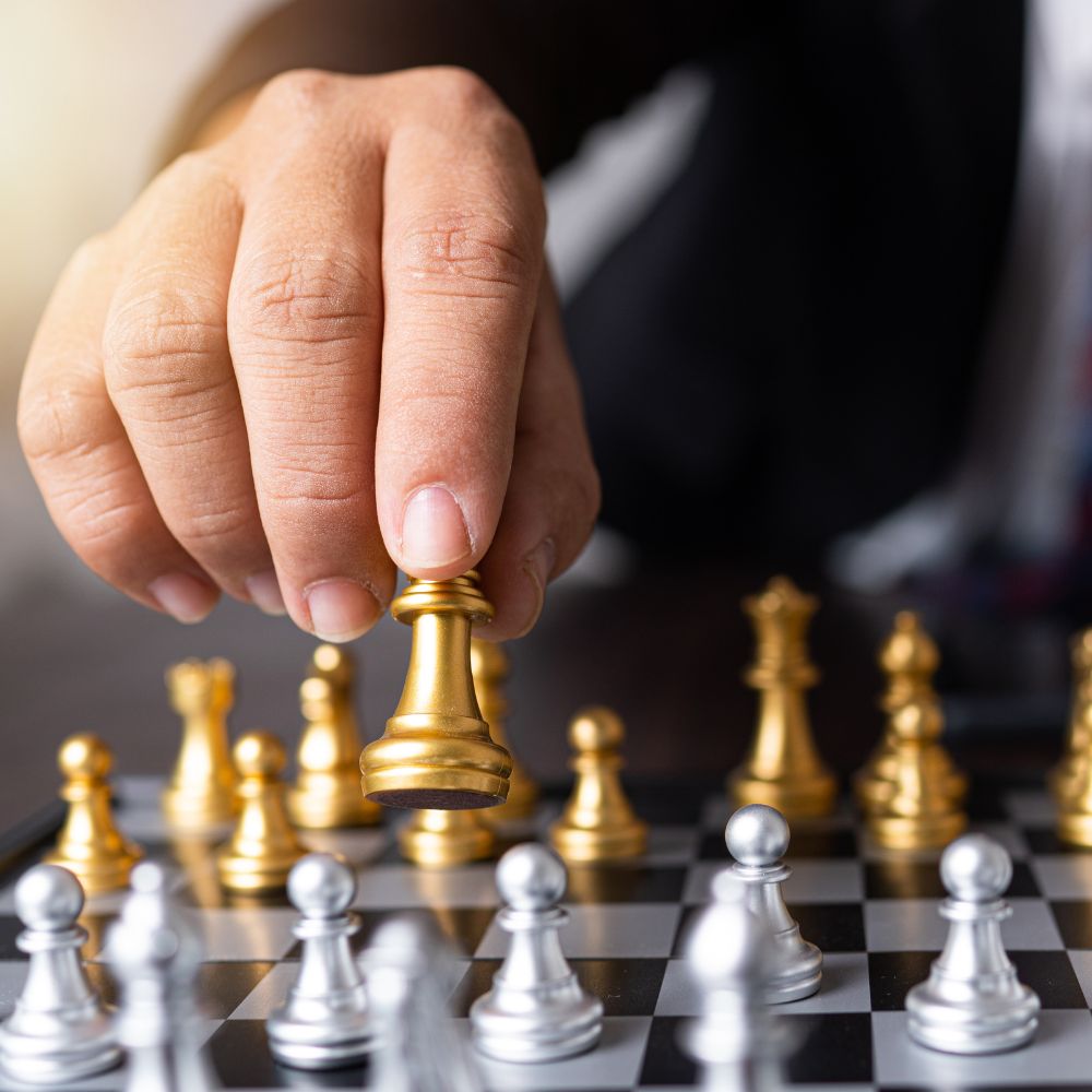 Main déplaçant une pièce d'échecs dorée, symbolisant des stratégies pour attirer des visiteurs à un kiosque d'exposition.