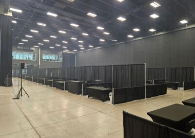 Salle d’exposition aménagée avec kiosques, tables et séparateurs noirs